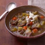 Mexican tomatillo and shredded beef soup in clay bowl
