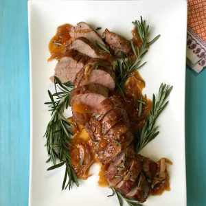 Pork Tenderloin With Rosemary Apricot Sauce on white platter