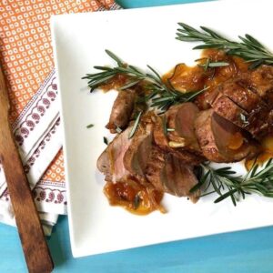 Sliced Pork Tenderloin With Rosemary Apricot Sauce on white platter