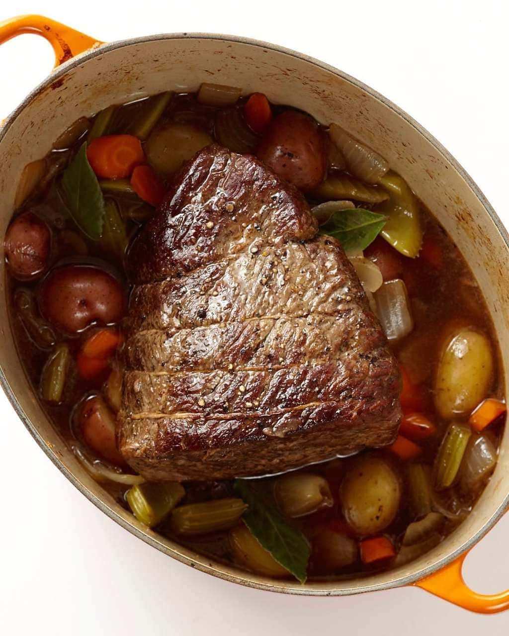 The Best Classic Pot Roast with potatoes and carrots overhead in LeCreuset pan