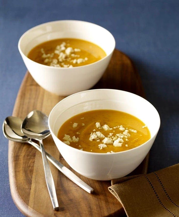 Chipotle Sweet Potato Soup with Queso Blanco in two white bowls w spoons on board and blue background