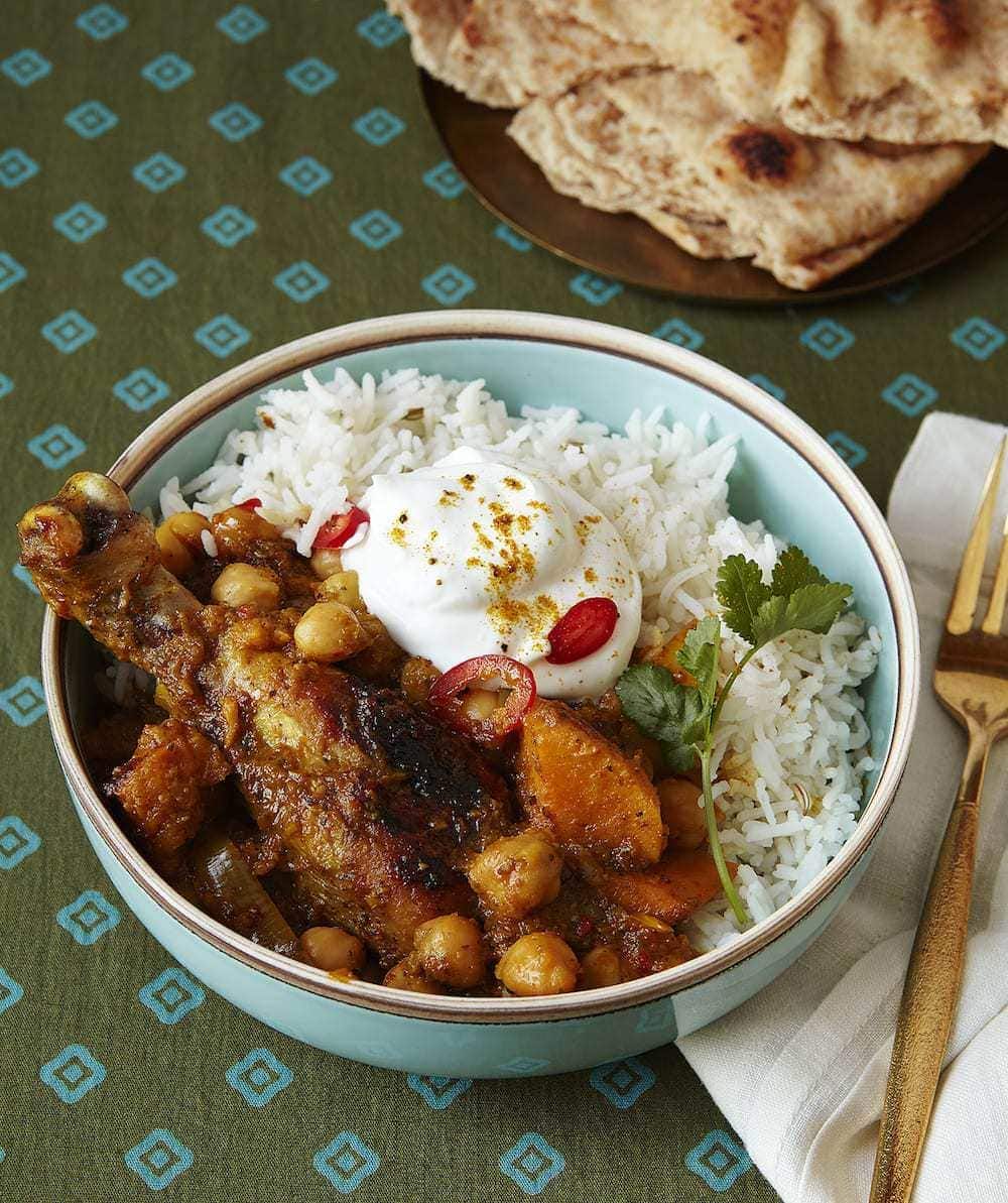 Curry Chicken Drumsticks with Chickpeas  served with rice and Yogurt in turquoise bowl with nann bread
