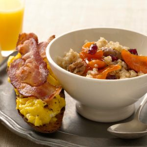 Close up of Cracked Wheat Cereal with Bacon and Egg Toasts on metallic plate