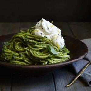 Fresh green pesto pasts in brown bowl with lemon cream