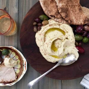 The Real Deal Creamy Hummus in brown bowl on wood surface