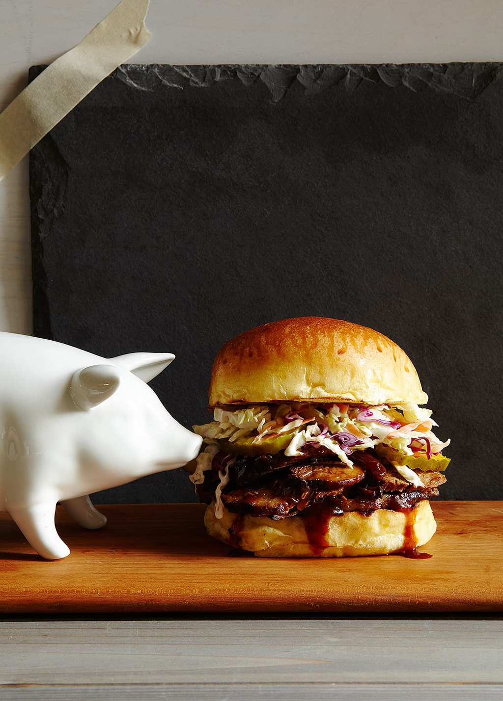 A BBQ brisket sandwich next to a porcelain pig. 