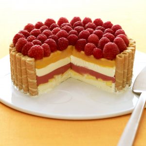 layered icebox cake with raspberries and mangos with slice missing