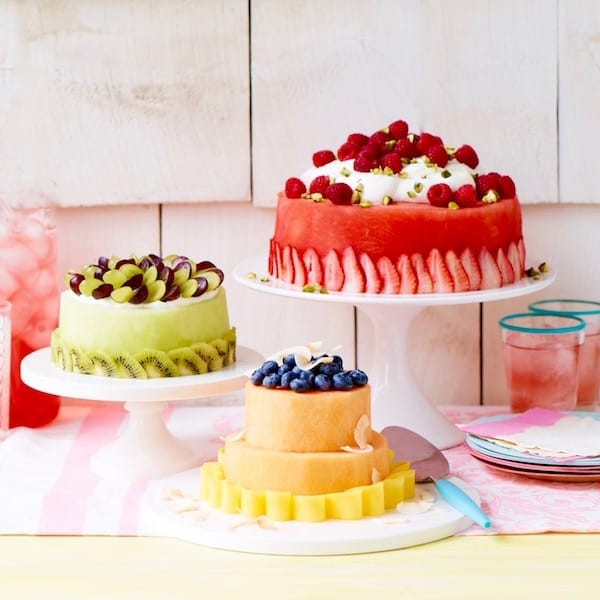 Three melon cakes on white cake stands with lemonade