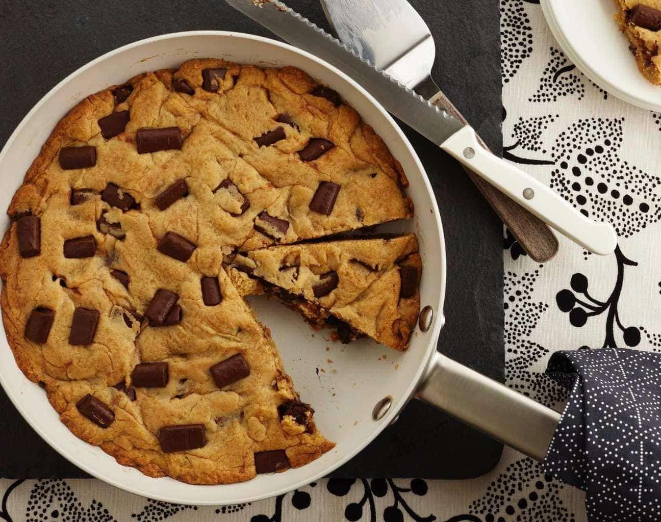 An overhead view of a chocolate chip skillet cookie, with a slice missing. 