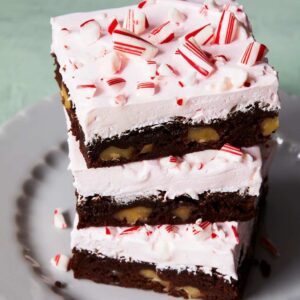 holiday peppermint brownies with pink frosting stack on a plate