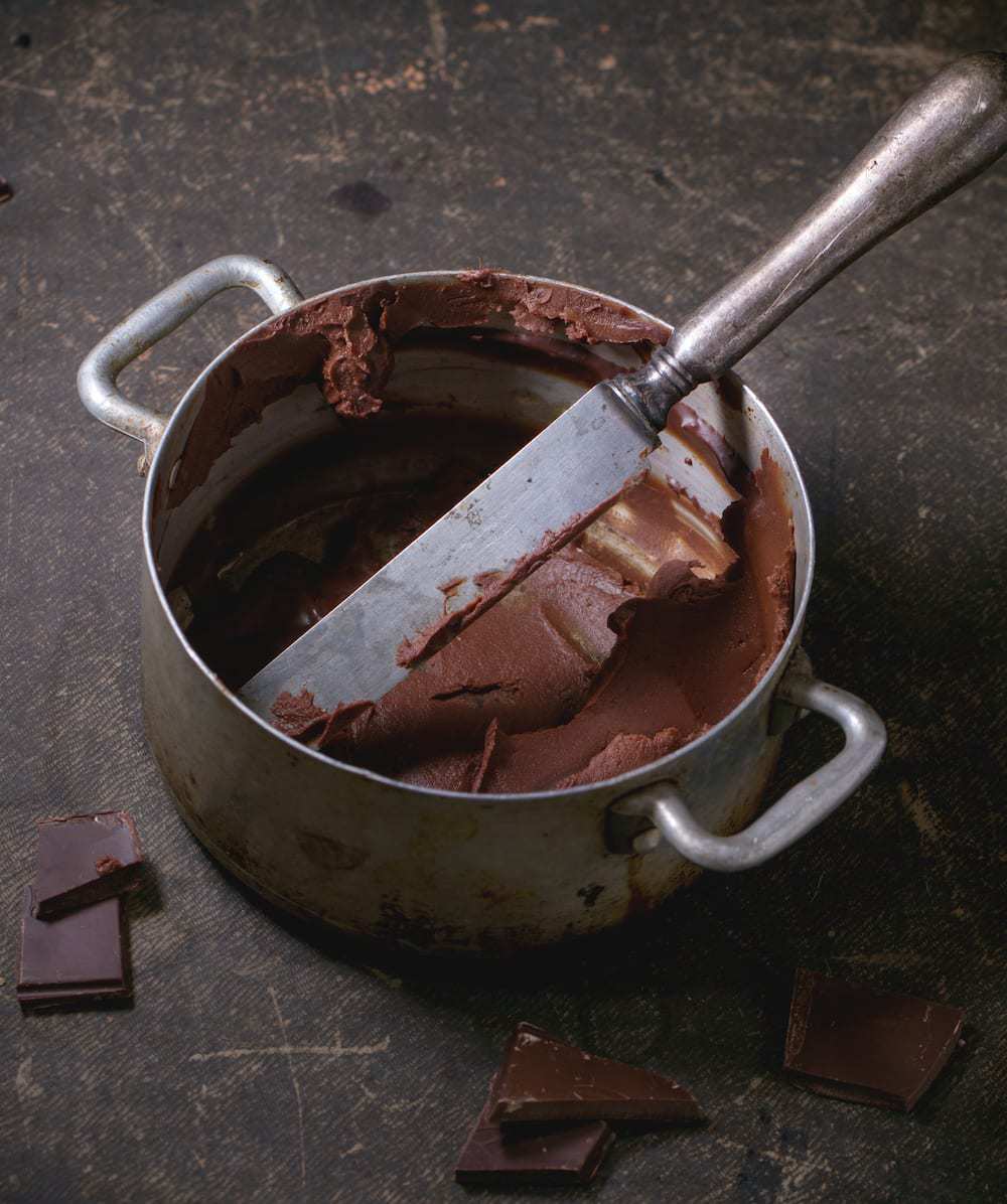 pan with chocolate ganache frosting remains over dark background