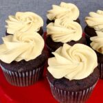 chocolate cupcakes with caramel icing on a red platter