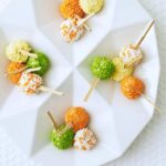 mini ice cream pops with orange, yellow and green candy sprinkles on white platter