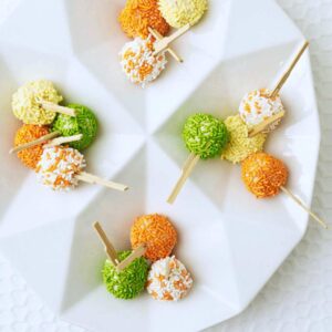 mini ice cream pops with orange, yellow and green candy sprinkles on white platter