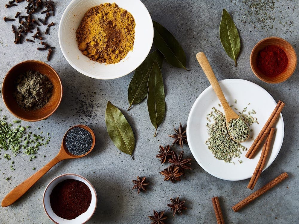 Spices in bowl and spoons on surface