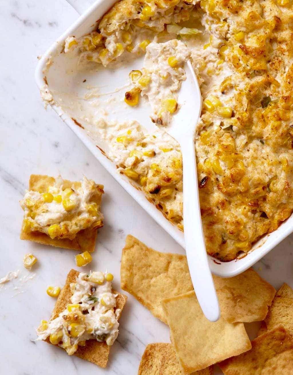 Grilled Corn and Crab Dip in white casserole with chips, close crop