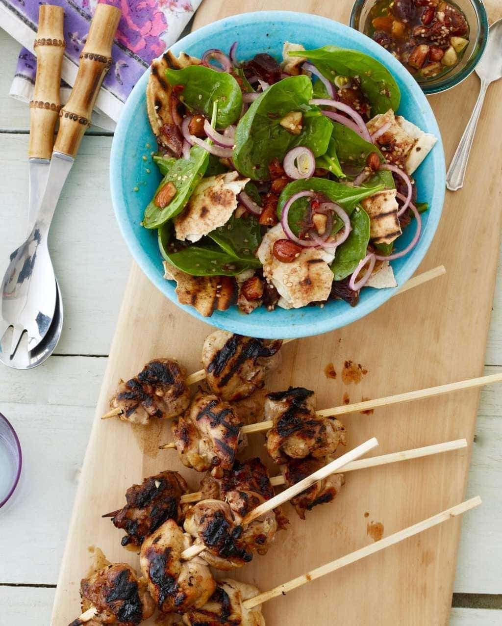 Fattoush Salad with Grilled lemon chicken kabobs in turquoise bowl and on cutting board.