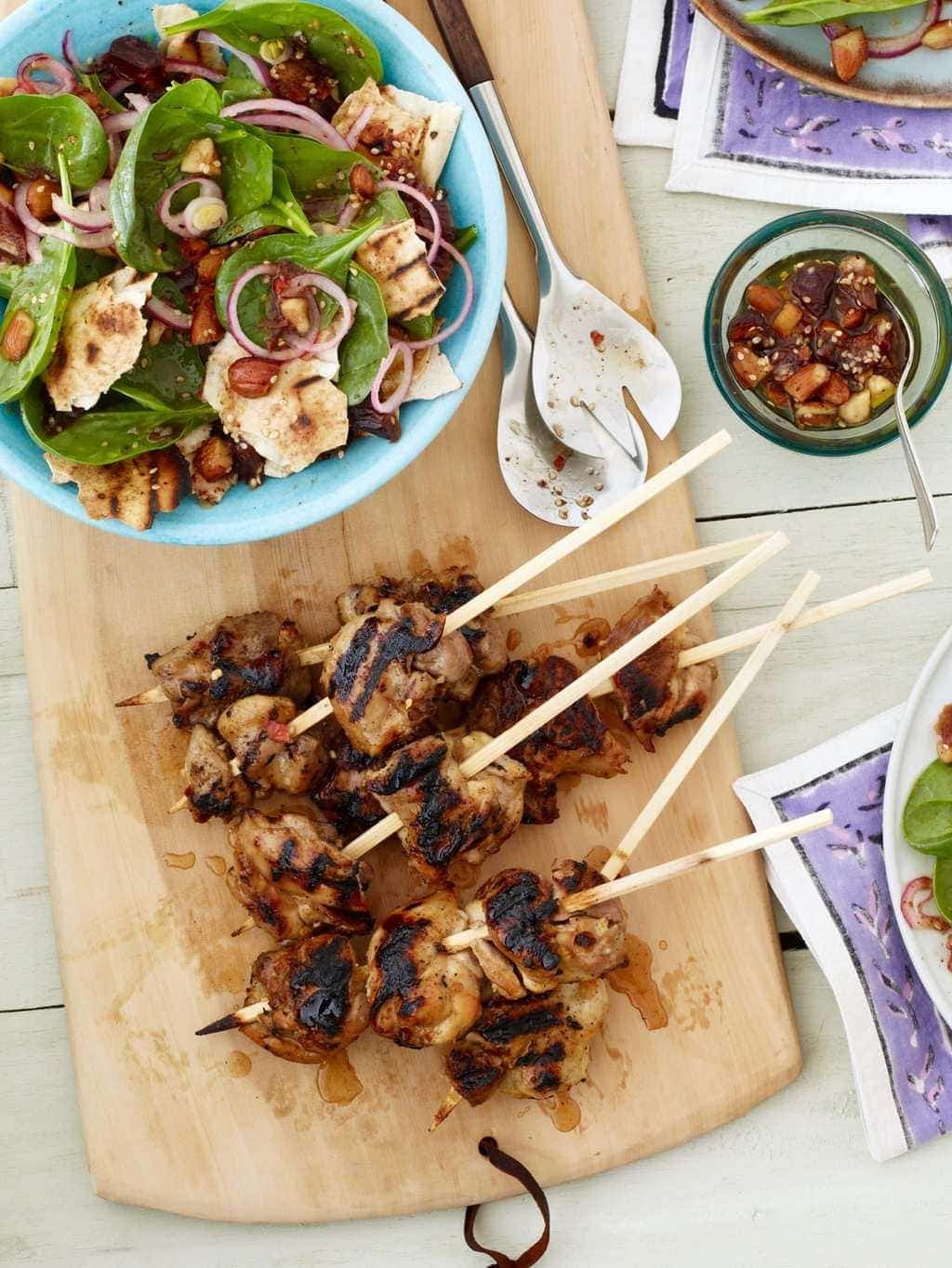 Kabobs and Salad on cutting board with condiments
