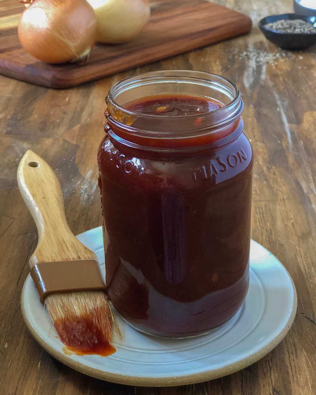 BBQ sauce in mason jar with onions and seasonings in background