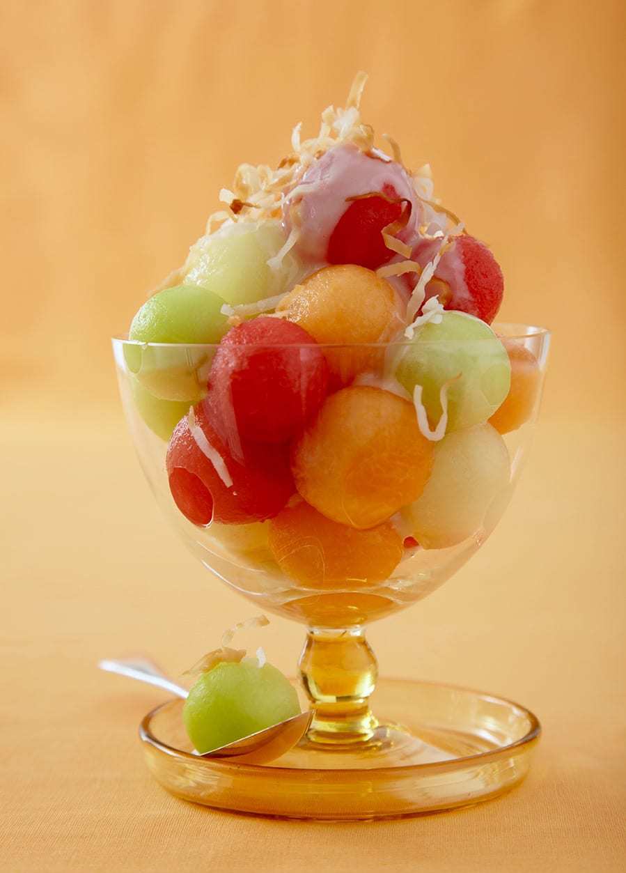 Summer melon dessert in footed glass on yellow background