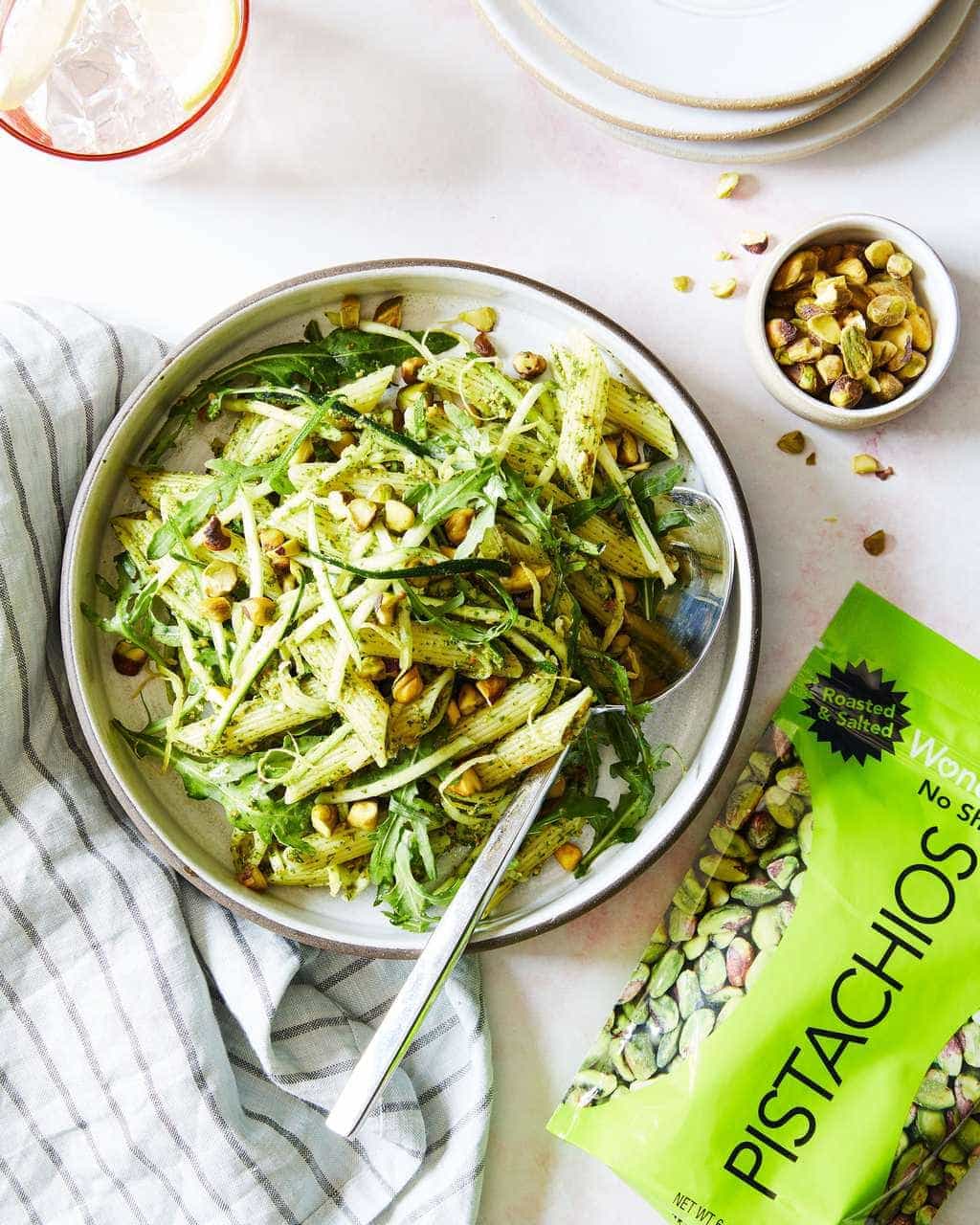 Bowl of pistachio pesto pasta with bag of green pistachios