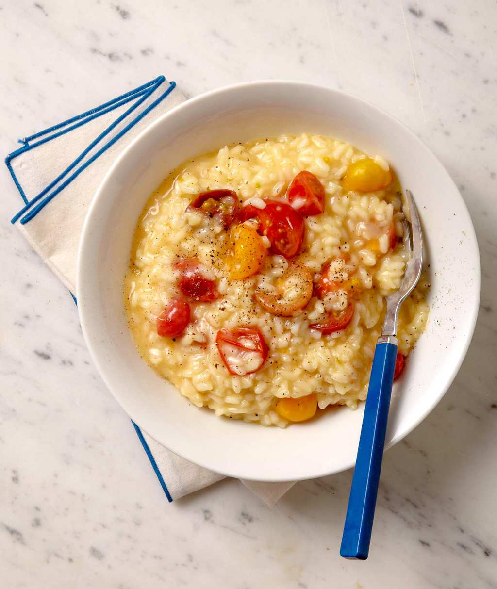 A bowl of easy risotto with cherry tomatoes and a blue fork