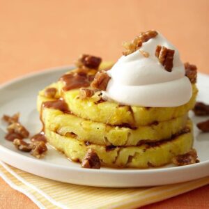 Grilled Pineapple Praline stacked on white plate with whipped cream