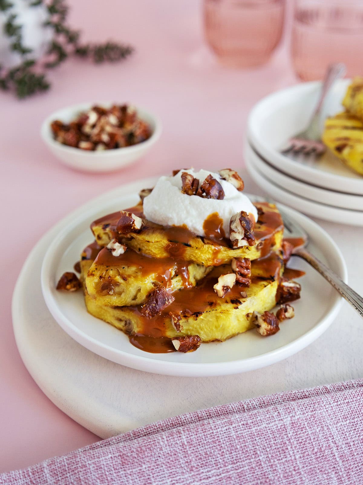 Close up of a plate topped with grilled pineapple covered in caramel and whipped cream.