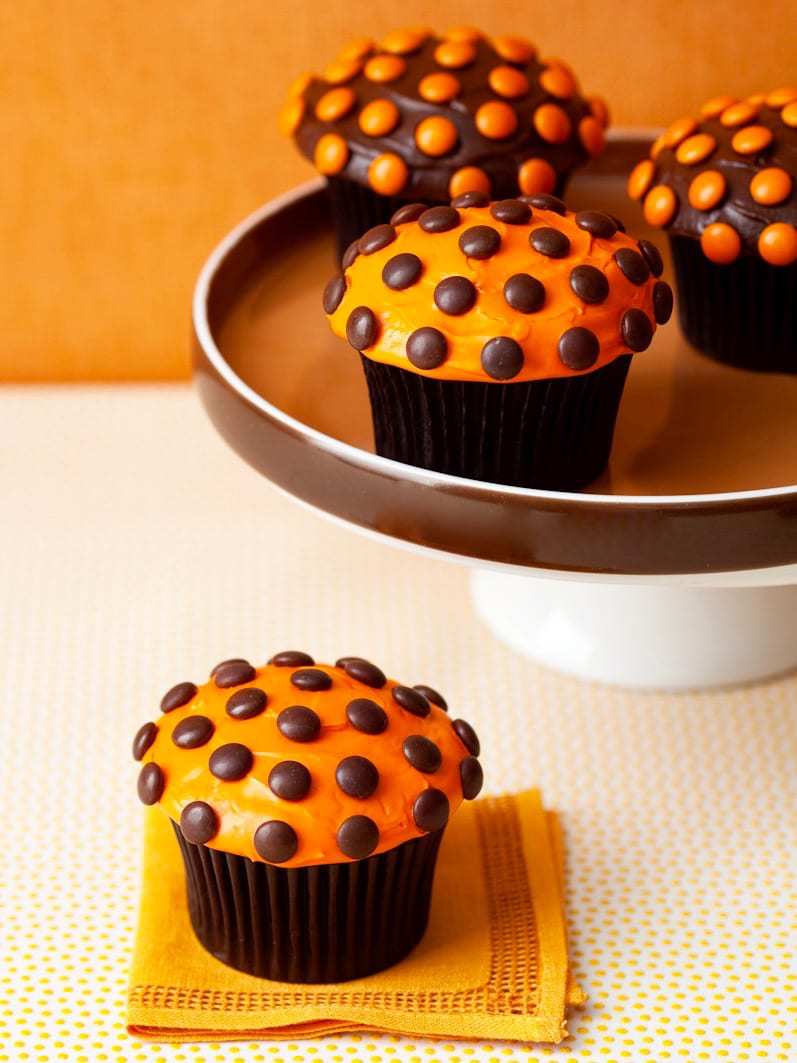 halloween cupcakes on a cake stand with orange background