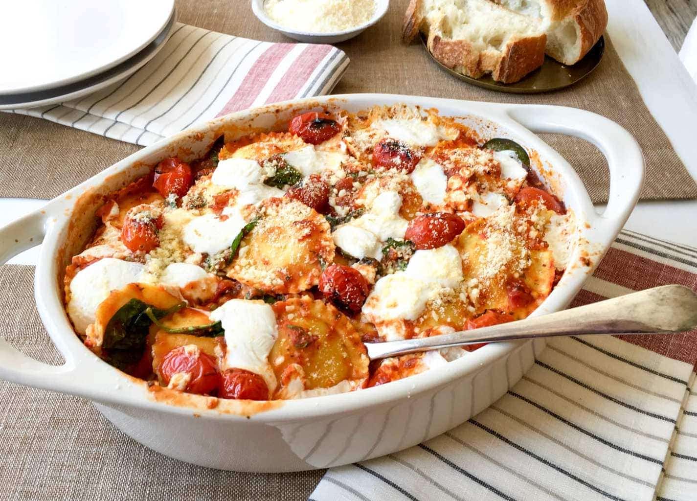 ravioli bake with fresh tomatoes and spinach in a casserole dish