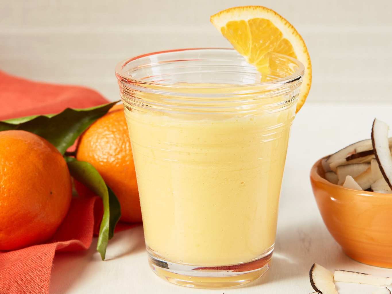 A mango smoothie with an orange wedge 