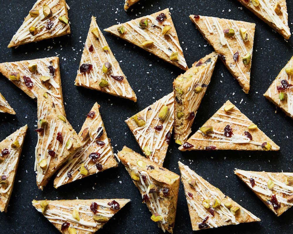 Cookie bars with pistachios and cherries on a black surface