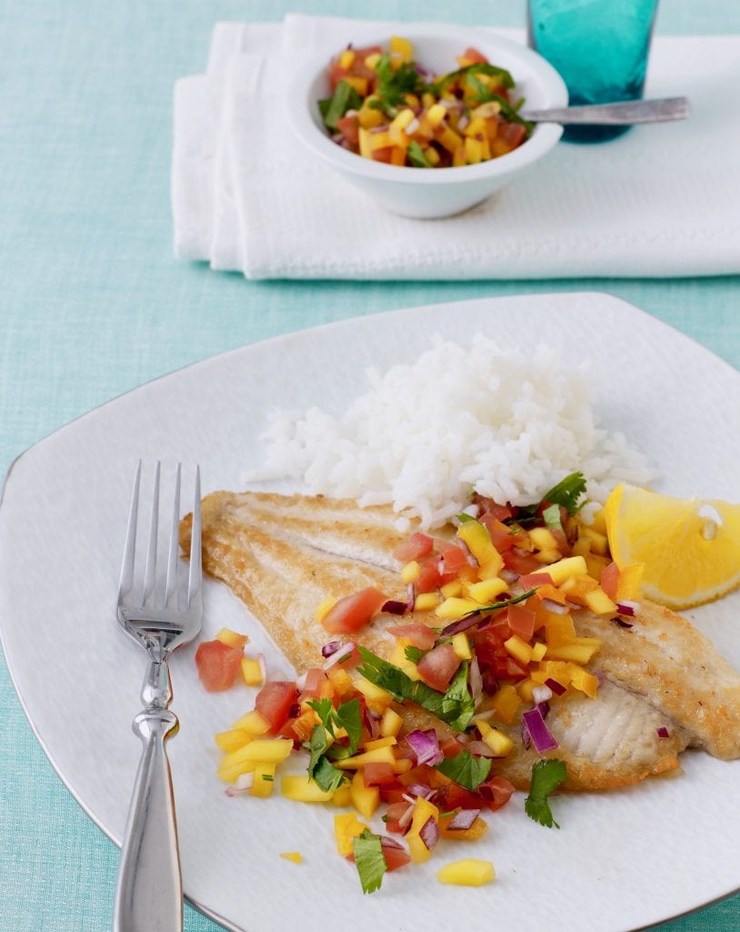 broiled fish with mango salsa on a plate with rice