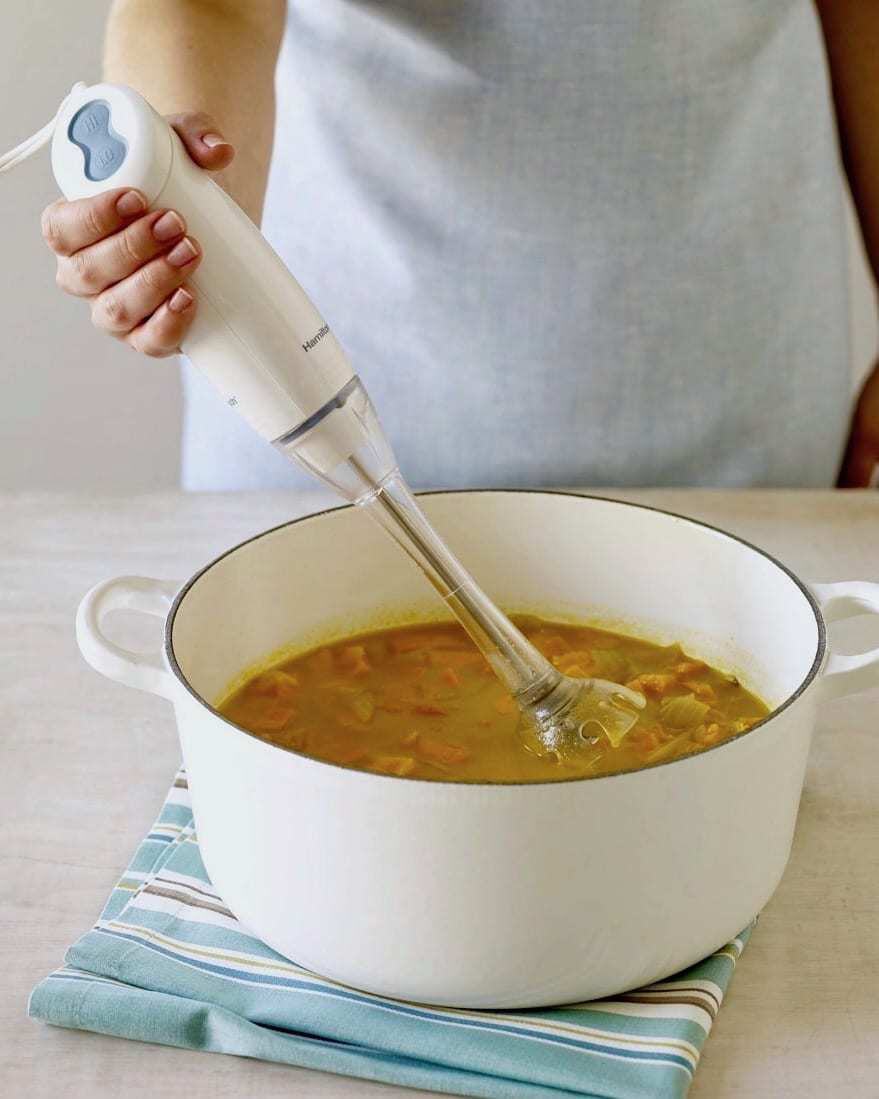 soup in white le crueset with immersion blender
