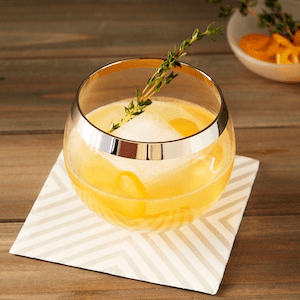 Kumquat Thyme Cocktail with bourbon on striped cocktail napkin