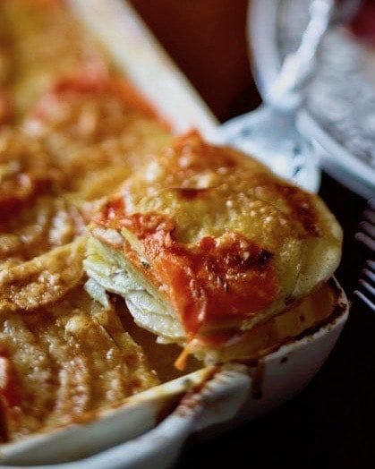 golden carrot and potato gratin in a dish cut square