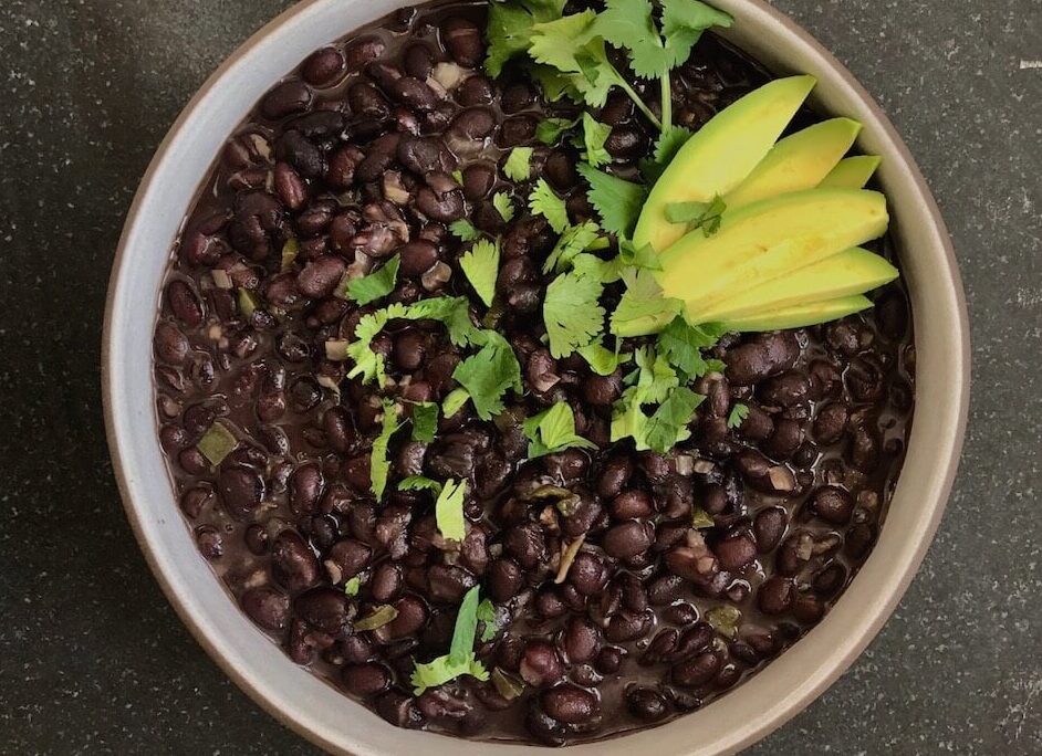 overhead view of cuban-style black beans with cilantro and avocado