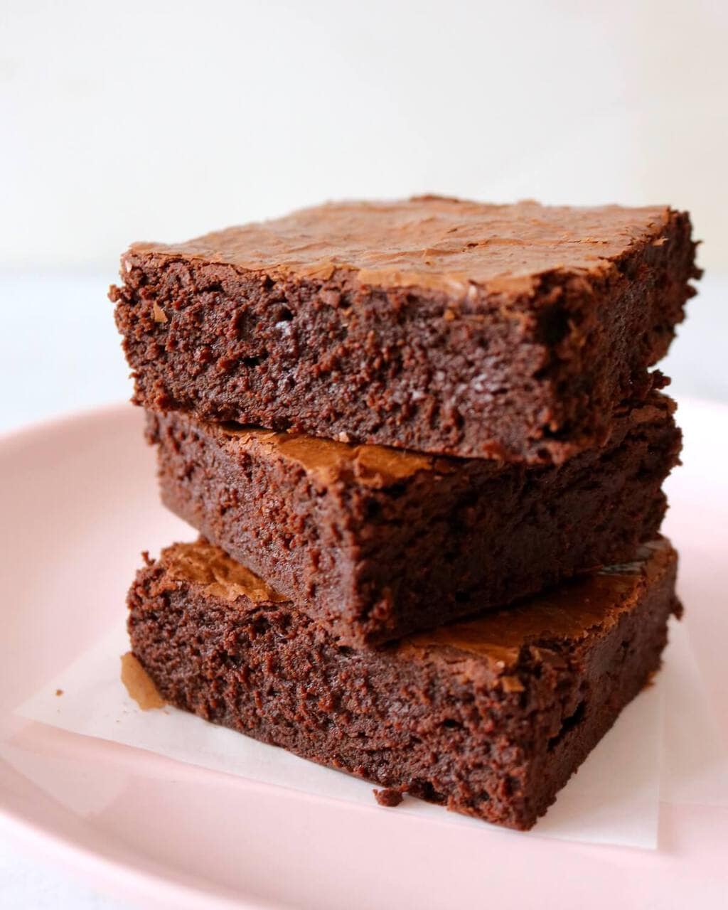 Stack of three chewy brownies on pink plate