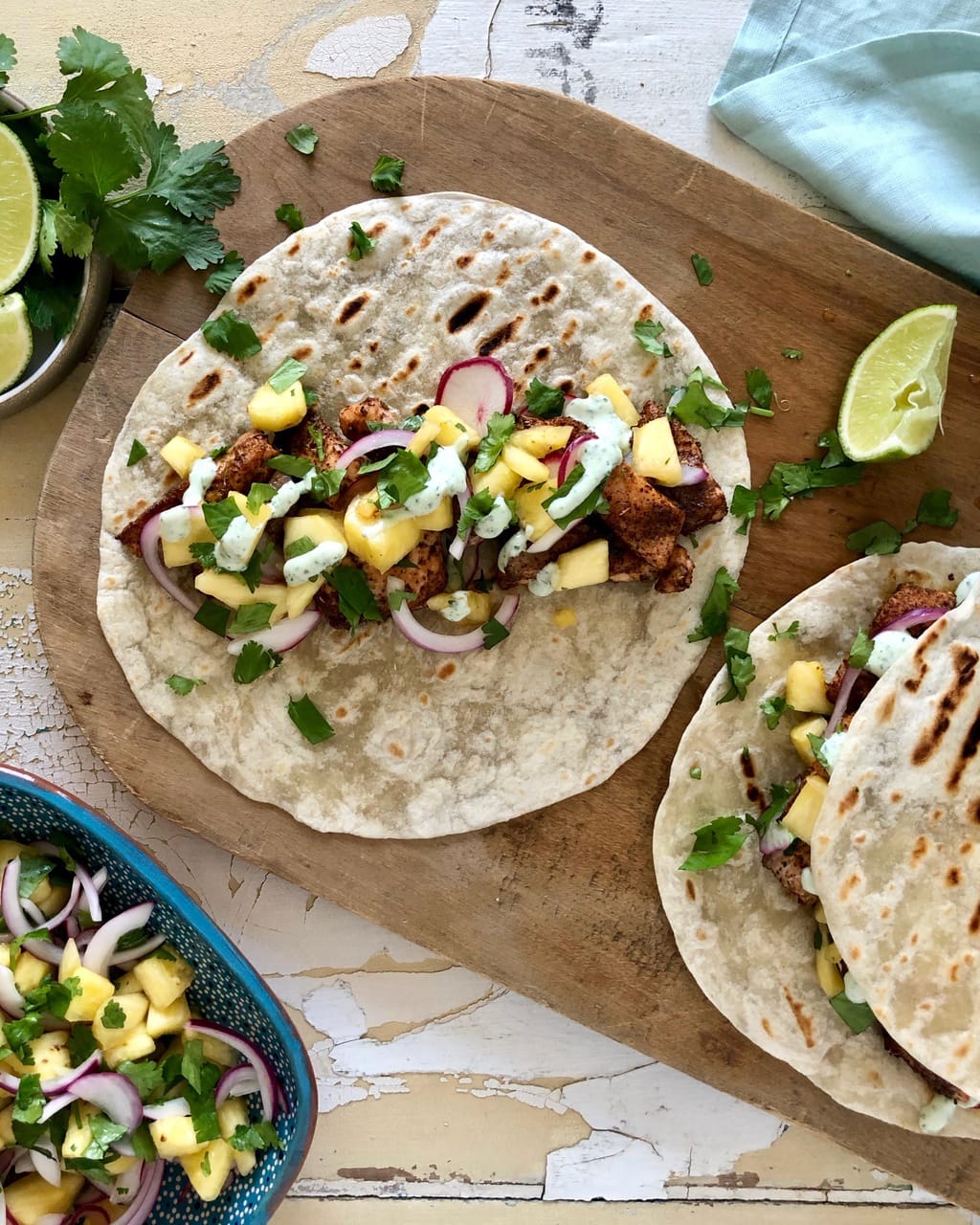 tacos with cilantro, lime wedges, and bowl of pineapple salsa