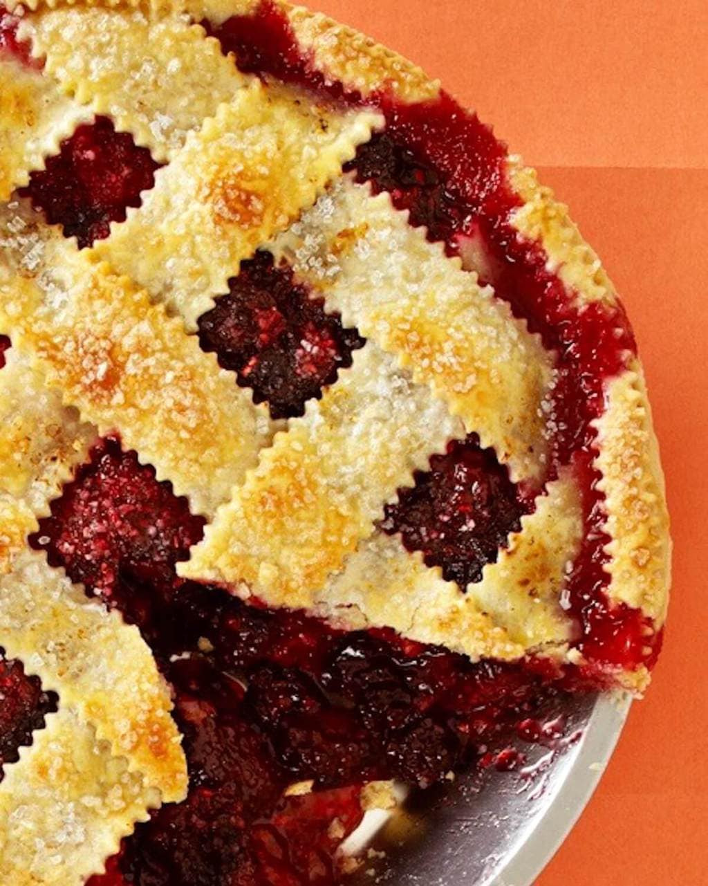 overhead view of a razzleberry pie with lattice top on orange paper