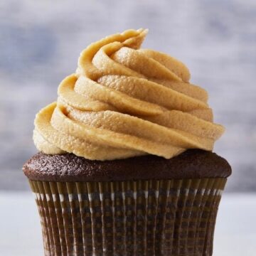 Peanut Butter Frosting swirled on Chocolate cupcake in brown and white striped paper baking cup