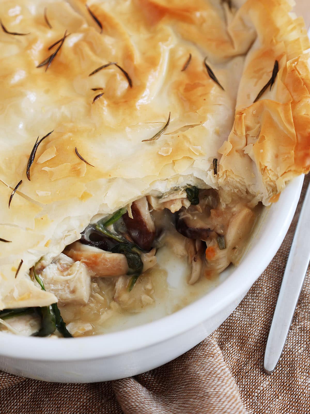 Close up of the top of a chicken spinach casserole where a serving has been removed to show filling.