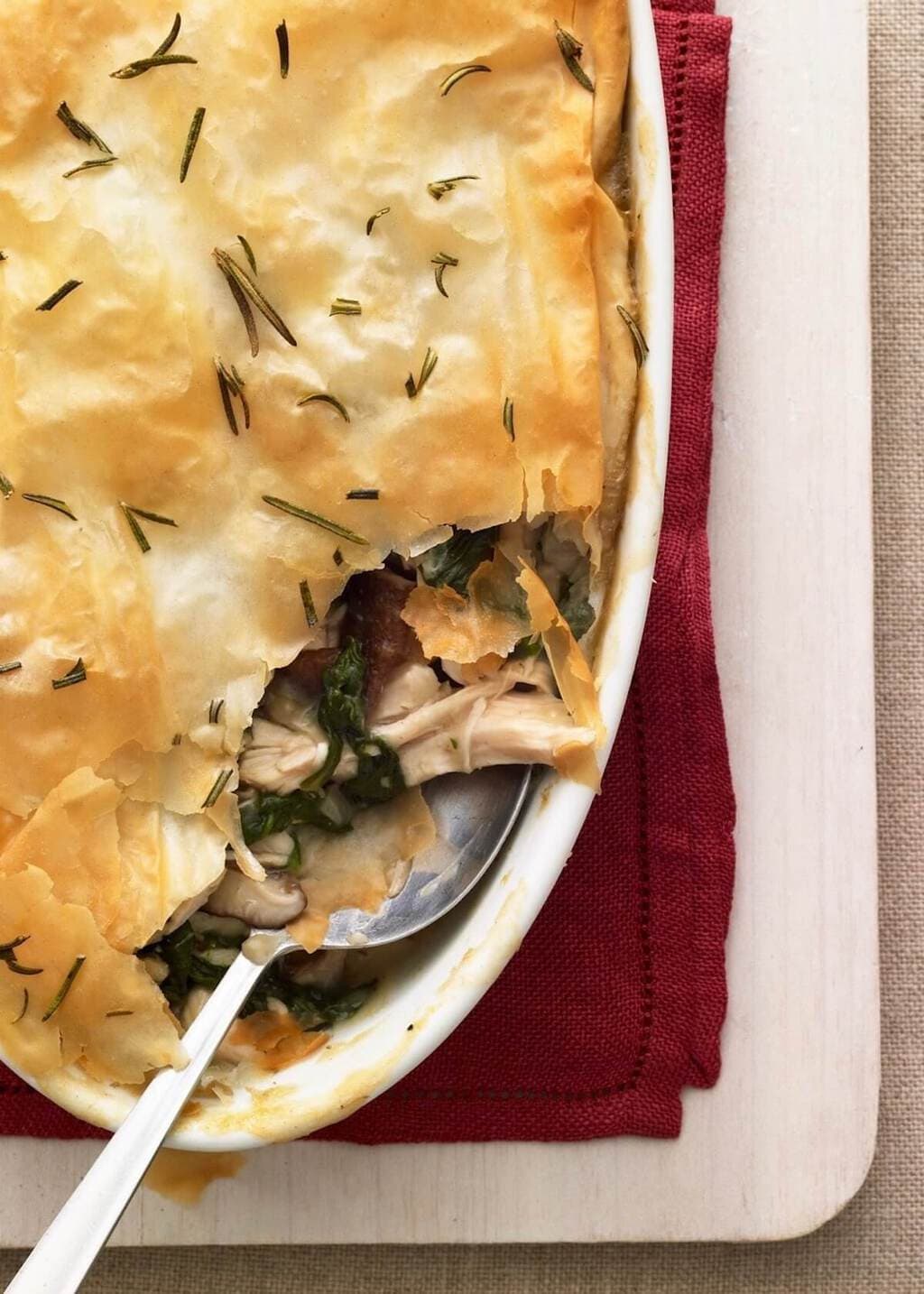 Chicken Spinach Mushroom Pie with serving spoon in white oval baking dish