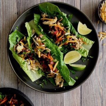 Overhead view of Healthy Taco Salad Lettuce Wraps on a plate with black beans chicken and slices of lime