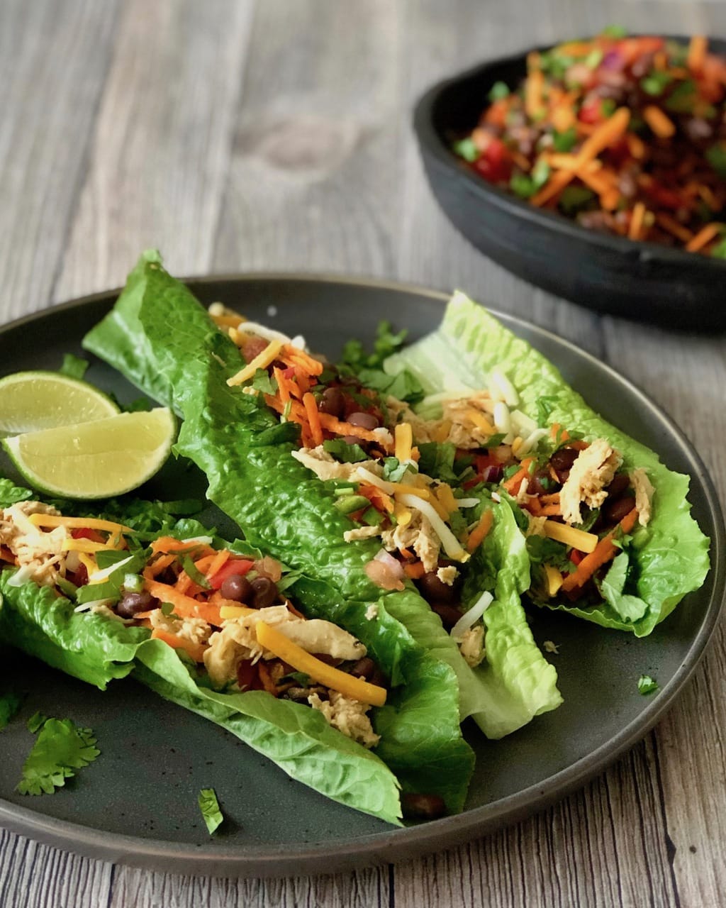 Healthy Taco Salad Lettuce Wraps on a plate with black beans chicken and slices of lime