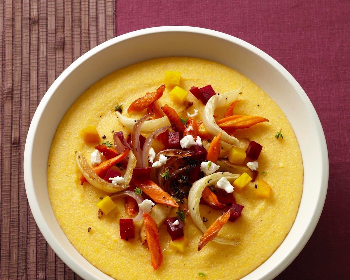 Creamy yellow polenta in a bowl topped with roasted vegetables