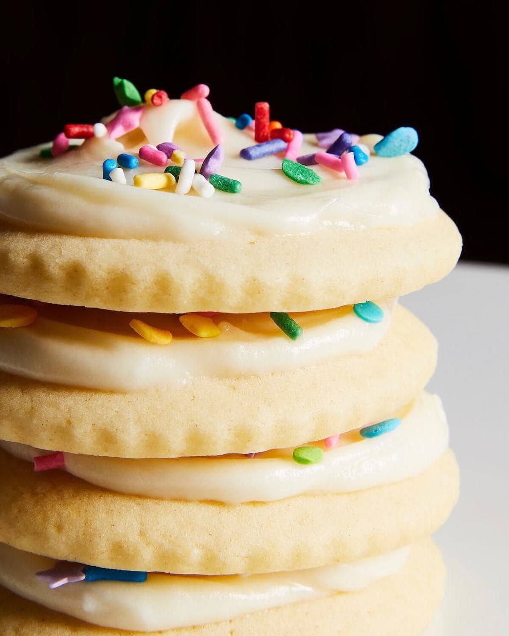 Stack of sugar cookies with cream cheese icing and sprinkles