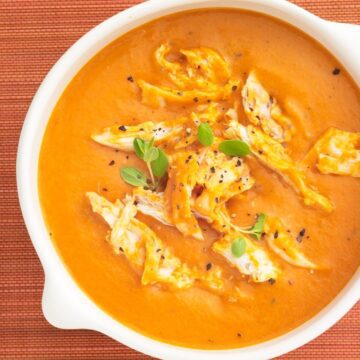 creamy tomato soup with chicken in a white bowl