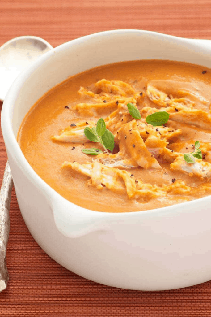 Creamy tomato soup with chicken in white bowl
