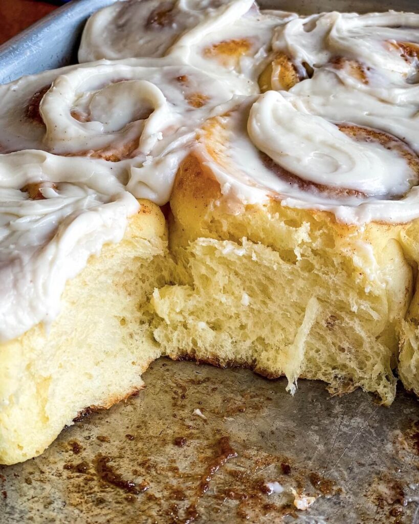 baked cinnamon rolls with frosting in pan